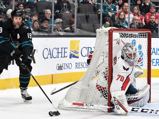 SAN JOSE, CA - FEBRUARY 14: Joe Thornton #19 of the San Jose Sharks skates with the puck behind Braden Holtby #70 of the Washington Capitals at SAP Center on February 14, 2019 in San Jose, California