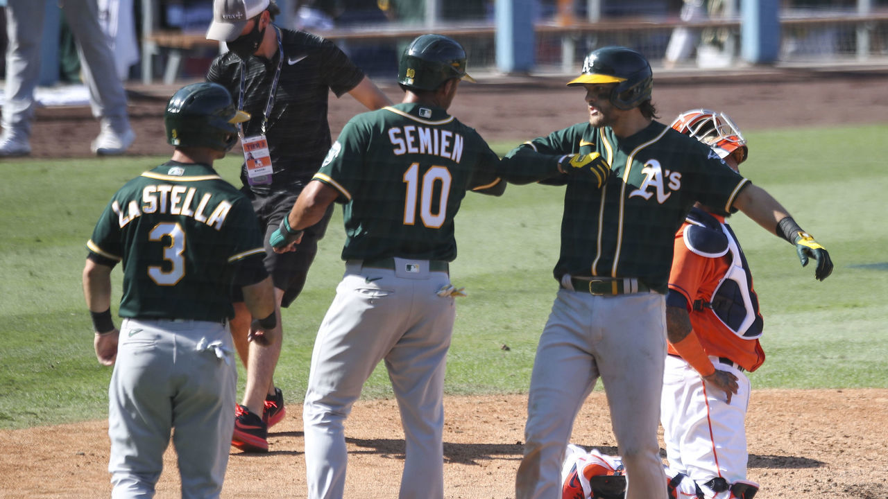 LOS ANGELES, CA - OCTOBER 07: Chad Pinder #18 of the Oakland Athletics celebrates with Marcus Semien #10 and Tommy La Stella #3 after hitting a three-run home run in the seventh inning during Game 3 of the ALDS between the Houston Astros and the Oakland Athletics at Dodger Stadium on Wednesday, October 7, 2020 in Los Angeles, California.