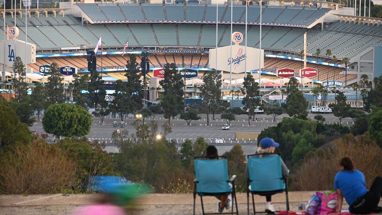 People looks out over Dodgers Stadium as the Los Angeles Dodgers play the San Francisco Giants in an empty stadium on the opening day of the coronavirus-abbreviated Major League Baseball (MLB) season, July 23, 2020 in Los Angeles. - The game is being played without fans in the stadium due to the COVID-19 pandemic.