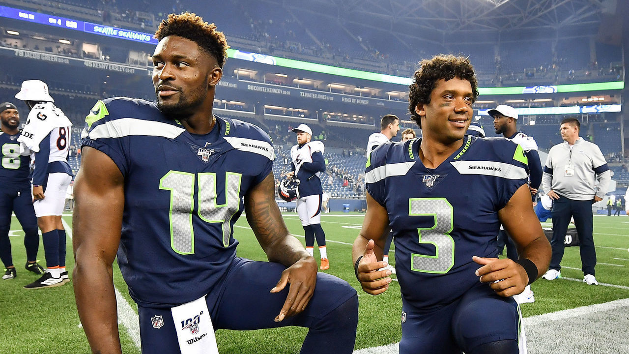 SEATTLE, WASHINGTON - AUGUST 08: D.K. Metcalf #14 and Russell Wilson #3 of the Seattle Seahawks take a knee after the preseason game victory over the Denver Broncos at CenturyLink Field on August 08, 2019 in Seattle, Washington.