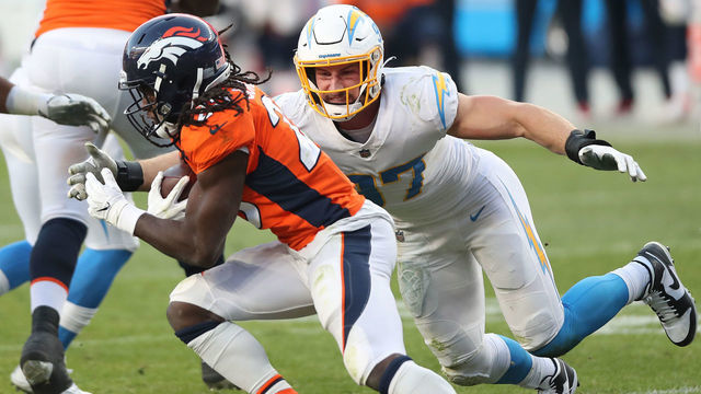 DENVER, COLORADO - NOVEMBER 01: Phillip Lindsay #30 of the Denver Broncos carries the ball against Joey Bosa #97 of the Los Angeles Chargers in the third quarter of the game at Empower Field At Mile High on November 01, 2020 in Denver, Colorado.