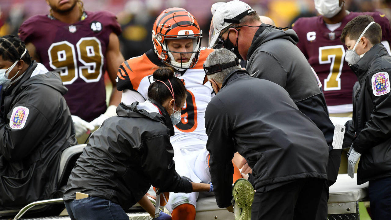 LANDOVER, MD - NOVEMBER 22: Doctors and athletic trainers help Bengals quarterback Joe Burrow (9) onto the medical cart after being injured as Washington defensive end Chase Young (99) and quarterback Dwayne Haskins, Jr. (7) watch during the Cincinnati Bengals vs. Washington Football Team NFL game at FedEx Field on November 22, 2020 in Landover, MD.