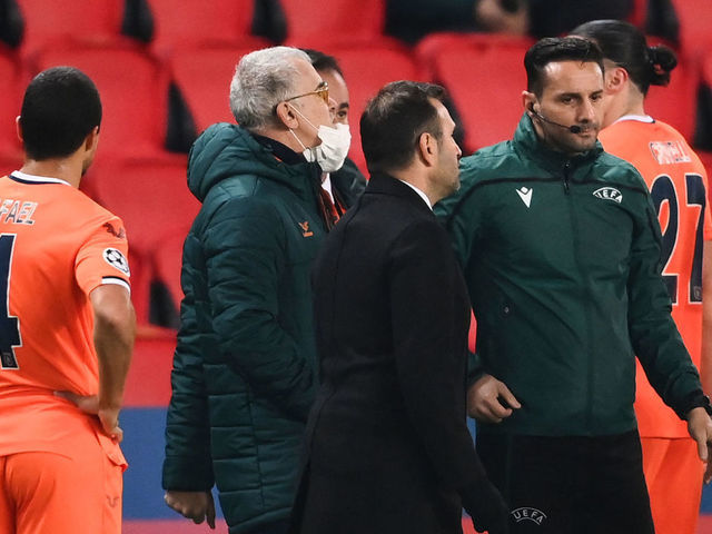 TOPSHOT - Istanbul Basaksehir's Turkish coach Okan Buruk (2ndR) talks to Romanian 4th referee Sebastian Coltescu (R) after the game was suspended in the first half as the players walked off amid allegations of racism by one of the match officials during the UEFA Champions League group H football match between Paris Saint-Germain (PSG) and Istanbul Basaksehir FK at the Parc des Princes stadium in Paris, on December 8, 2020. - Paris Saint-Germain's decisive Champions League game with Istanbul Basaksehir was suspended today in the first half as the players walked off amid allegations of racism by one of the match officials. The row erupted after Basaksehir assistant coach Pierre Webo, the former Cameroon international, was shown a red card during a fierce row on the touchline with staff from the Turkish club appearing to accuse the Romanian fourth official of using a racist term.