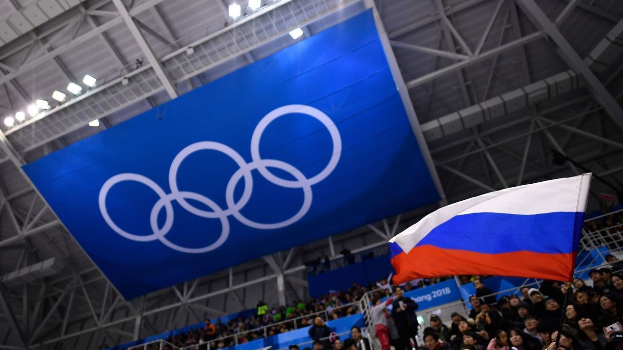 A spectator waves the Russia flag during the men's preliminary round ice hockey match between the Olympic Athletes from Russia and Slovenia during the Pyeongchang 2018 Winter Olympic Games at the Gangneung Hockey Centre in Gangneung on February 16, 2018. / AFP PHOTO / Brendan Smialowski