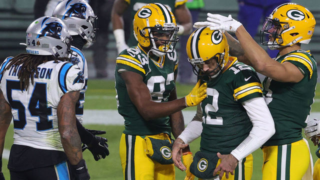 GREEN BAY, WISCONSIN - DECEMBER 19: Quarterback Aaron Rodgers #12 of the Green Bay Packers celebrates with teammates after rushing for a touchdown during the second quarter of the game against the Carolina Panthers at Lambeau Field on December 19, 2020 in Green Bay, Wisconsin.