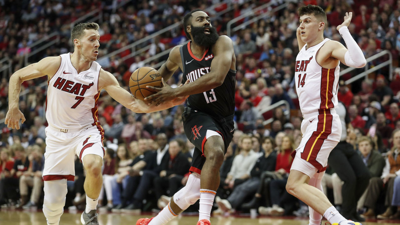 HOUSTON, TX - NOVEMBER 27: James Harden #13 of the Houston Rockets drives to the basket defended by Goran Dragic #7 of the Miami Heat and Tyler Herro #14 in the first half at Toyota Center on November 27, 2019 in Houston, Texas.