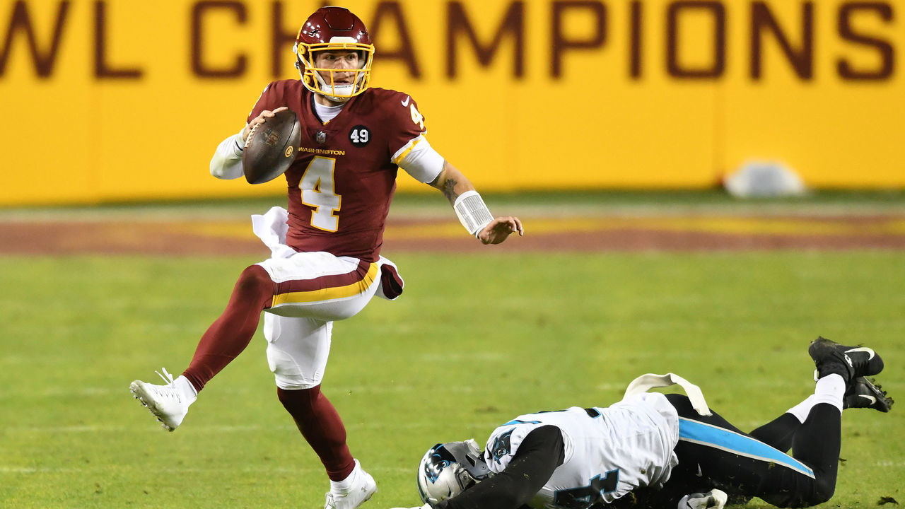 LANDOVER, MARYLAND - DECEMBER 27: Taylor Heinicke #4 of the Washington Football Team scrambles with the ball away from the tackle of Efe Obada #94 of the Carolina Panthers during the third quarter at FedExField on December 27, 2020 in Landover, Maryland.