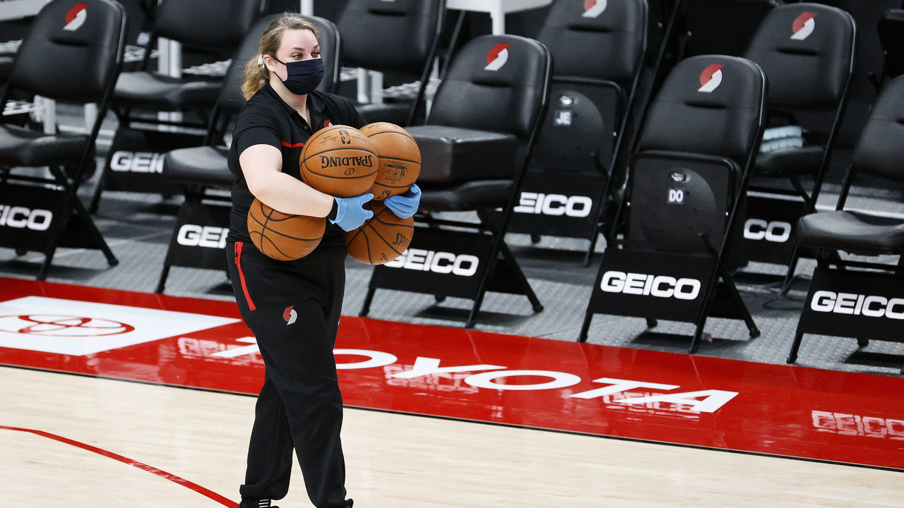PORTLAND, OREGON - DECEMBER 23: A masked worker retrieves basketballs before the game between the Portland Trail Blazers and the Utah Jazz at Moda Center on December 23, 2020 in Portland, Oregon.