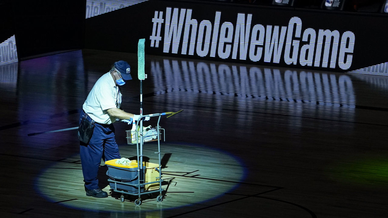 LAKE BUENA VISTA, FLORIDA - AUGUST 05: A worker prepares to clean the backboard following an NBA basketball game between the Washington Wizards and the Philadelphia 76ers at The Arena at ESPN Wide World Of Sports Complex on August 5, 2020 in Lake Buena Vista, Florida.