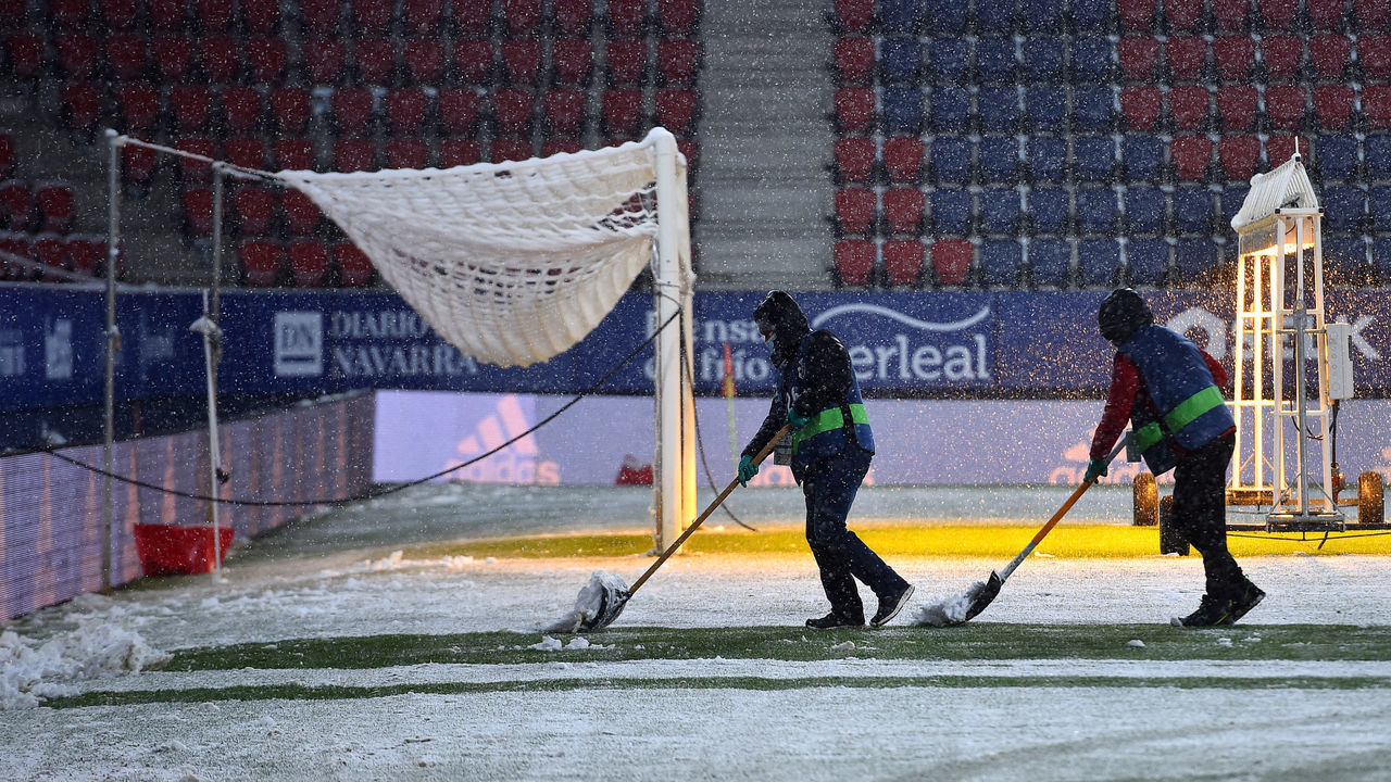 PAMPLONA, SPAIN - JANUARY 09: Ground staff work on the pitch to clear snow prior to the La Liga Santander match between C.A. Osasuna and Real Madrid at Estadio El Sadar on January 09, 2021 in Pamplona, Spain. Sporting stadiums around Spain remain under strict restrictions due to the Coronavirus Pandemic as Government social distancing laws prohibit fans inside venues resulting in games being played behind closed doors.
