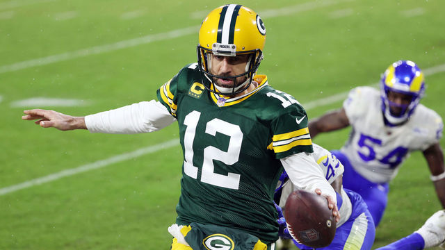GREEN BAY, WISCONSIN - JANUARY 16: Aaron Rodgers #12 of the Green Bay Packers runs for a 1-yard touchdown in the second quarter against the Los Angeles Rams during the NFC Divisional Playoff game at Lambeau Field on January 16, 2021 in Green Bay, Wisconsin.