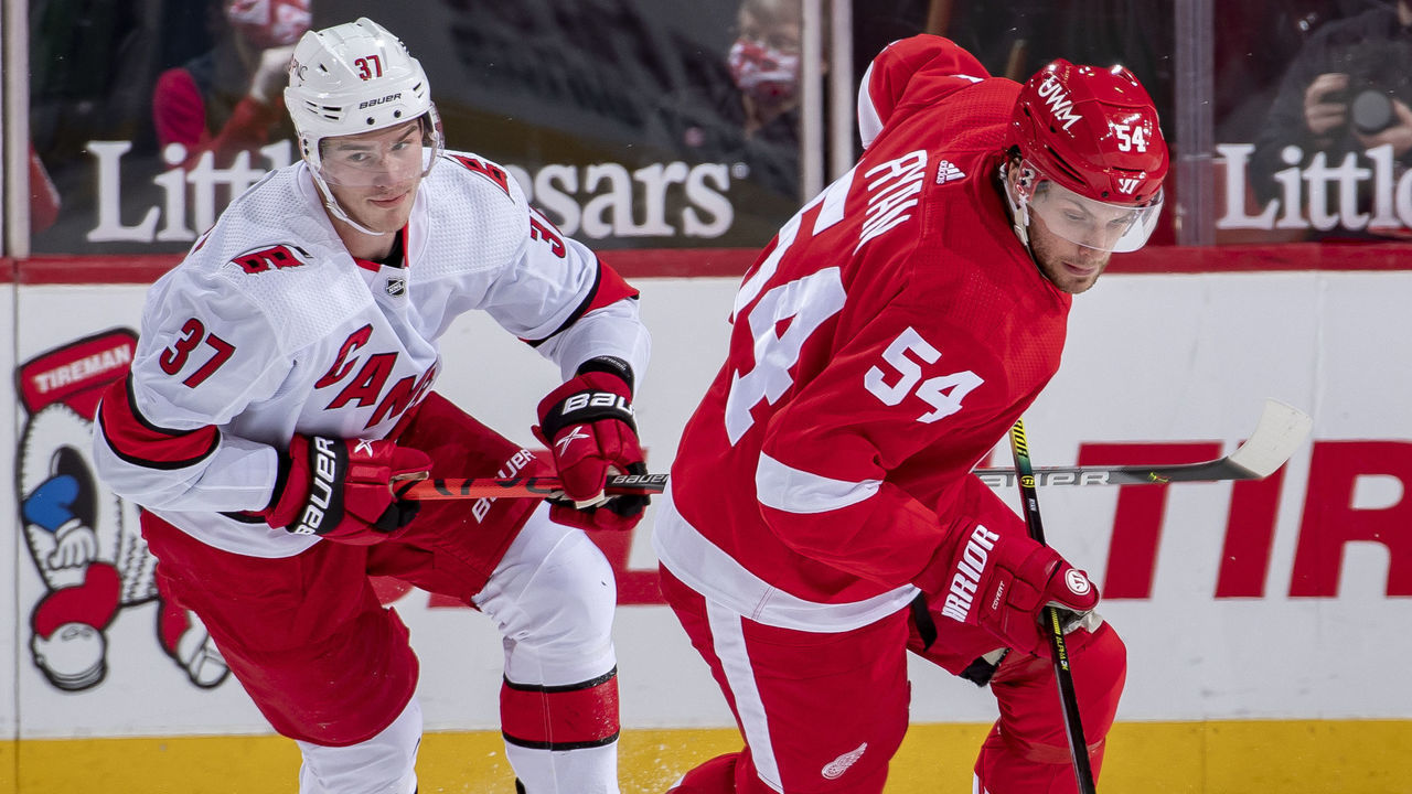 DETROIT, MI - JANUARY 16: Bobby Ryan #54 of the Detroit Red Wings turns up ice with the puck as Andrei Svechnikov #37 of the Carolina Hurricanes gives chase during an NHL game at Little Caesars Arena on January 16, 2021 in Detroit, Michigan.