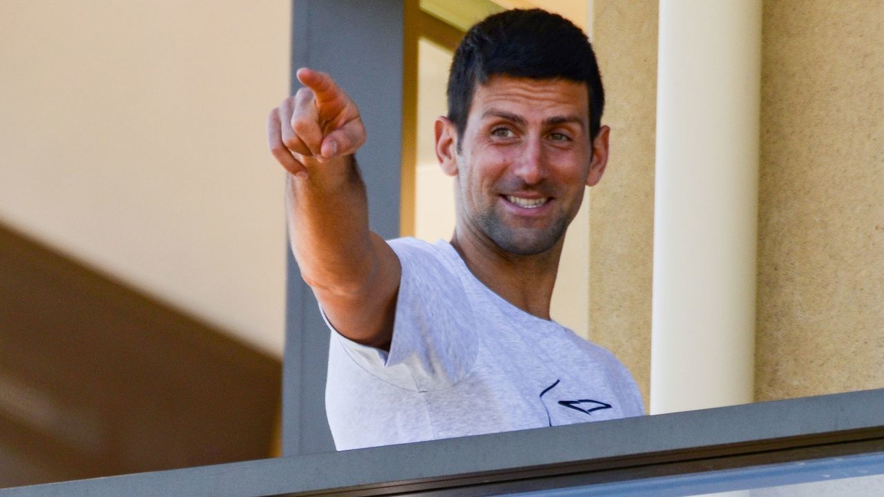 Men's world number one tennis player Novak Djokovic of Serbia gestures from his hotel balcony in Adelaide on January 18, 2021, one of the locations where players have quarantined for two weeks upon their arrival ahead of the Australian Open tennis tournament in Melbourne.