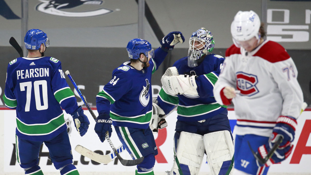 VANCOUVER, BC - JANUARY 20: Tyler Toffoli #73 of the Montreal Canadiens looks on dejected as Tanner Pearson #70, Tyler Motte #64, and Braden Holtby #49 of the Vancouver Canucks celebrate after winning their NHL game at Rogers Arena January 20, 2021 in Vancouver, British Columbia, Canada. Vancouver won 6-5.