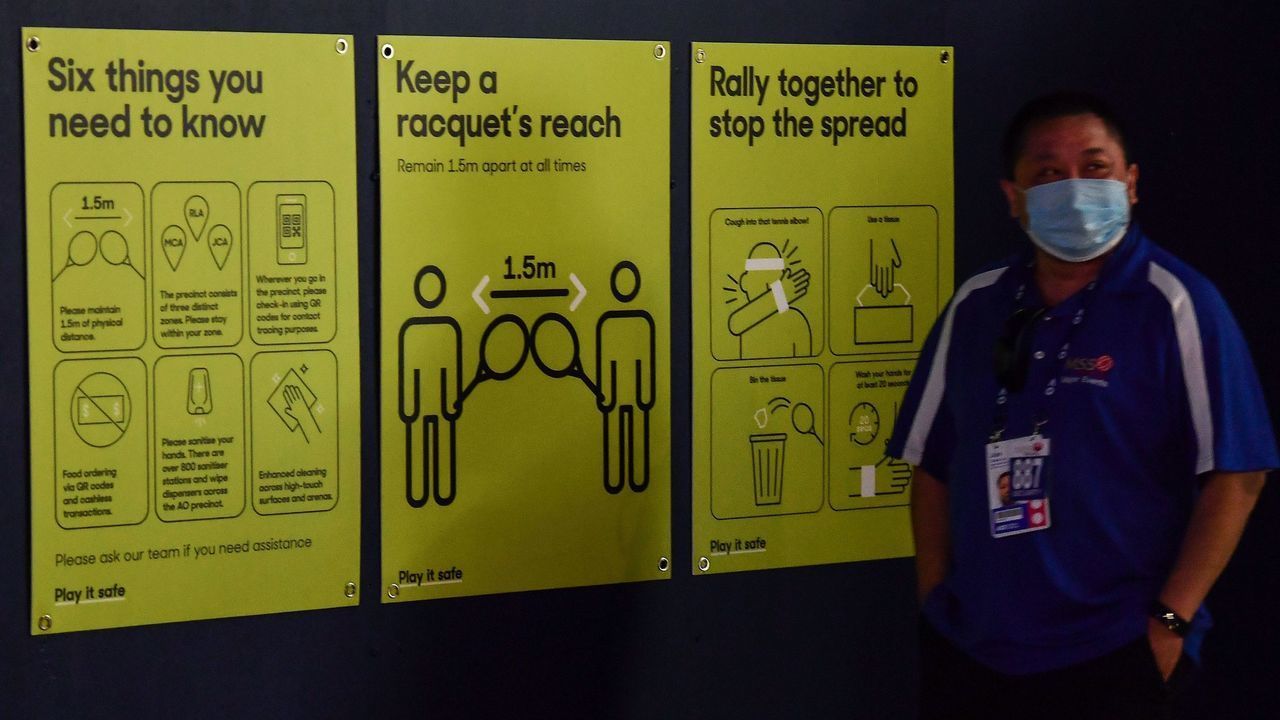 A man walks past signs related to the Covid-19 coronavirus in Melbourne on February 3, 2021 after between 500 and 600 tennis players and officials in Melbourne for the Australian Open were told to isolate and get tested Wednesday after a worker at one of the hotels they use tested positive for Covid-19.