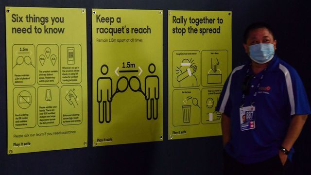 A man walks past signs related to the Covid-19 coronavirus in Melbourne on February 3, 2021 after between 500 and 600 tennis players and officials in Melbourne for the Australian Open were told to isolate and get tested Wednesday after a worker at one of the hotels they use tested positive for Covid-19.