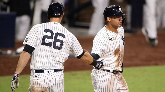 SAN DIEGO, CALIFORNIA - OCTOBER 08: Gleyber Torres #25 of the New York Yankees is congratulated by DJ LeMahieu #26 after scoring a run against the Tampa Bay Rays during the eighth inning in Game Four of the American League Division Series at PETCO Park on October 08, 2020 in San Diego, California.