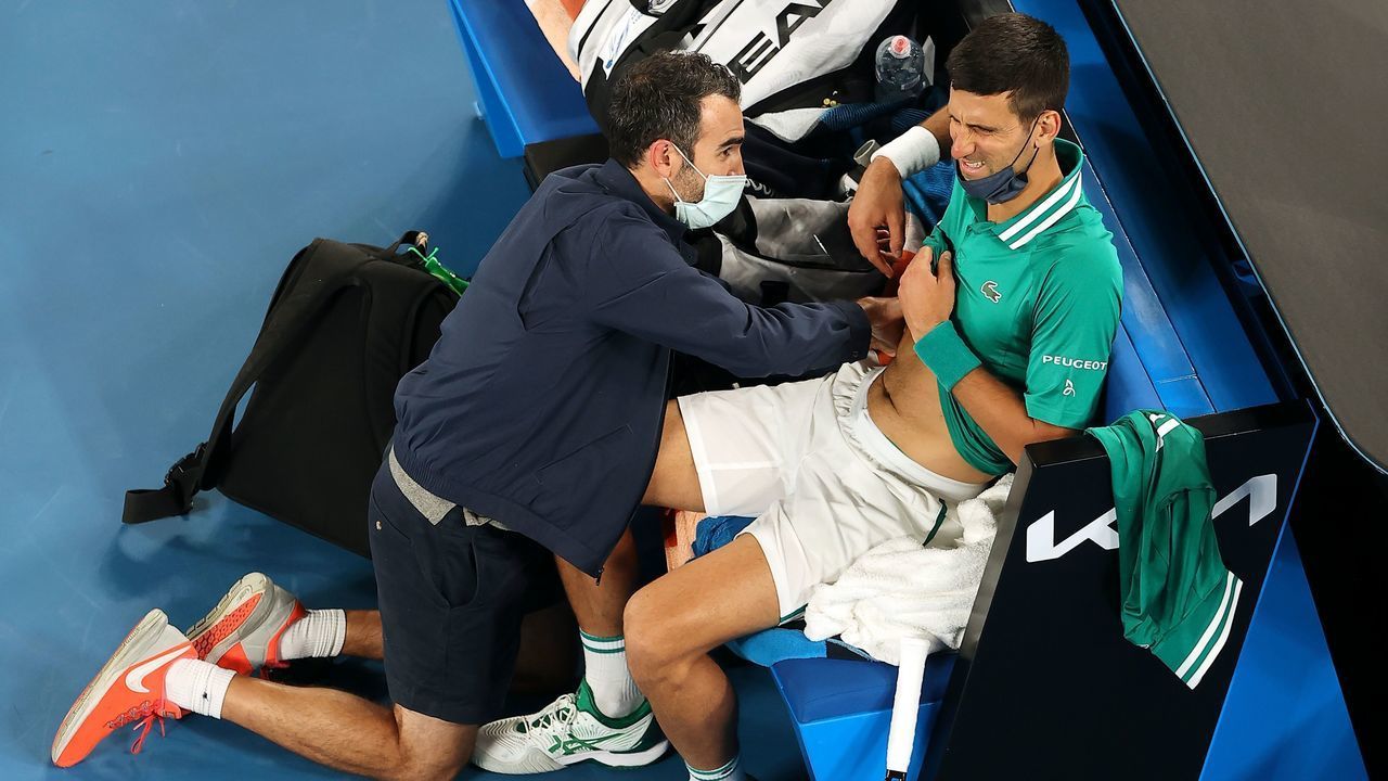 TOPSHOT - Serbia's Novak Djokovic gets medical treatment while playing against Taylor Fritz of the US during their men's singles match on day five of the Australian Open tennis tournament in Melbourne on February 12, 2021.