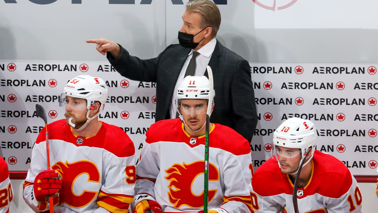 WINNIPEG, MANITOBA - JANUARY 14: Head Coach Geoff Ward of the Calgary Flames gives instructions behind players Sam Bennett #93, Mikael Backlund #11, and Derek Ryan #10 during second period action against the Winnipeg Jets at Bell MTS Place on January 14, 2021 in Winnipeg, Manitoba.