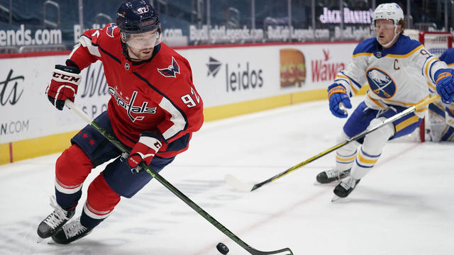 WASHINGTON, DC - FEBRUARY 18: Evgeny Kuznetsov #92 of the Washington Capitals skates with the puck against Jack Eichel #9 of the Buffalo Sabres in the first period at Capital One Arena on February 18, 2021 in Washington, DC.