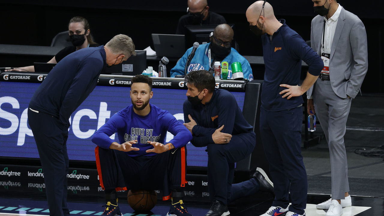 CHARLOTTE, NORTH CAROLINA - FEBRUARY 20: Stephen Curry #30 of the Golden State Warriors speaks with head coach Steve Kerr (L) and staff prior to their game against the Charlotte Hornets at Spectrum Center on February 20, 2021 in Charlotte, North Carolina.