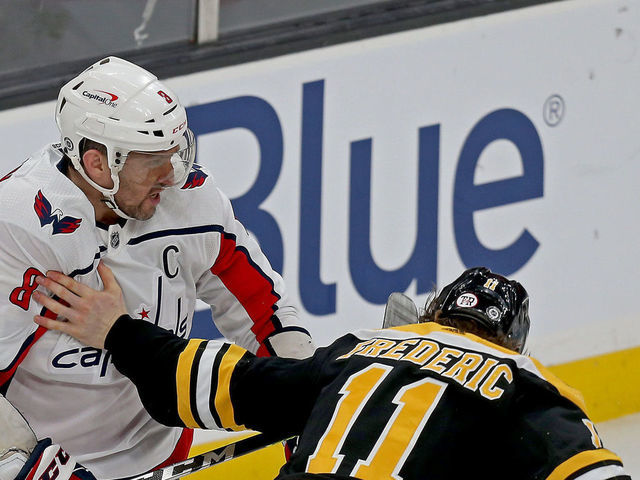 Boston, MA. - March 3: Trent Frederic #11 of the Boston Bruins takes his gloves off to try to fight with Alex Ovechkin #8 of the Washington Capitals during the third period of the NHL game at the TD garden on March 3, 2021 in Boston, Massachusetts. (Staff Photo By Matt Stone/MediaNews Group/Boston Herald)