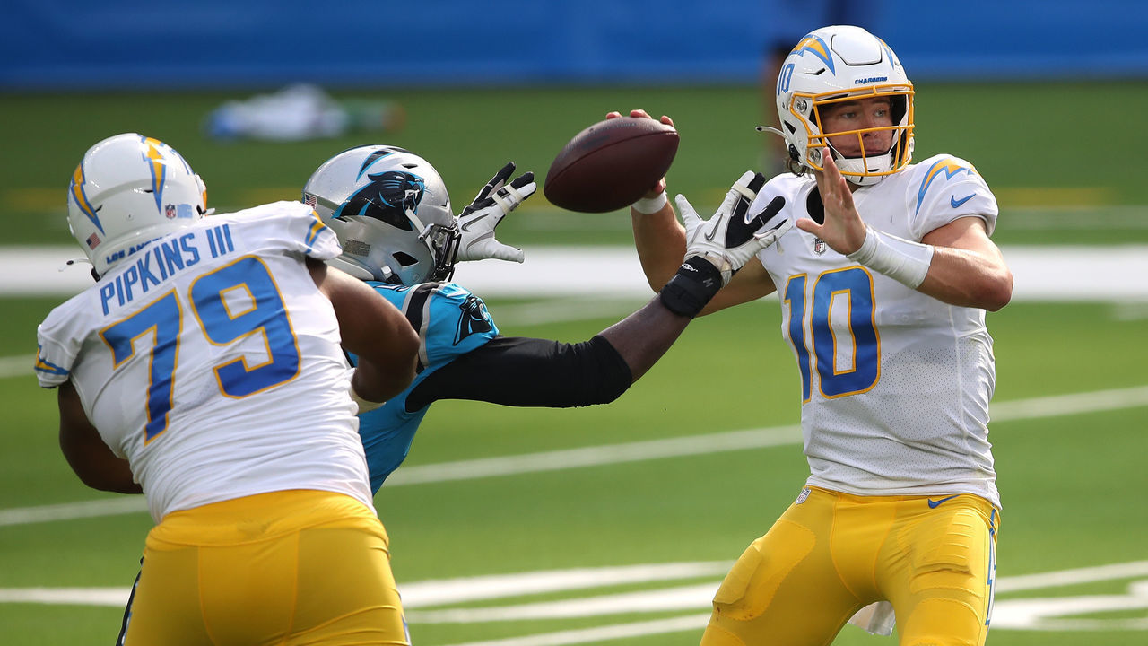 INGLEWOOD, CALIFORNIA - SEPTEMBER 27: Justin Herbert #10 of the Los Angeles Chargers passes the ball under pressure from Brian Burns #53 of the Carolina Panthers during the second half of a game against the Carolina Panthers at SoFi Stadium on September 27, 2020 in Inglewood, California.