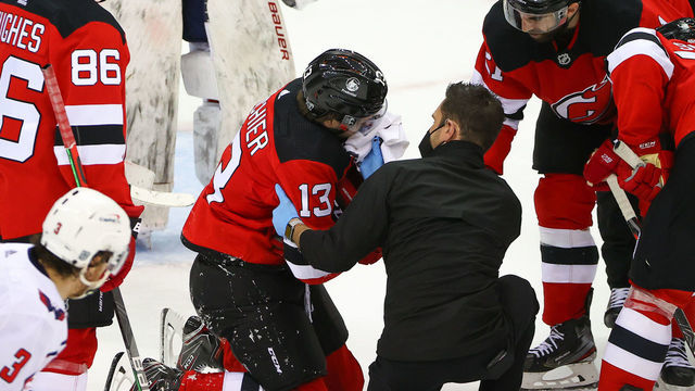 NEWARK, NJ - FEBRUARY 27: New Jersey Devils center Nico Hischier (13) is hit up high with the puck and is injured during the third period of the National Hockey League game between the New Jersey Devils and the Washington Capitals on February 26, 2021 at the PrudentialCenterin Newark, NJ.