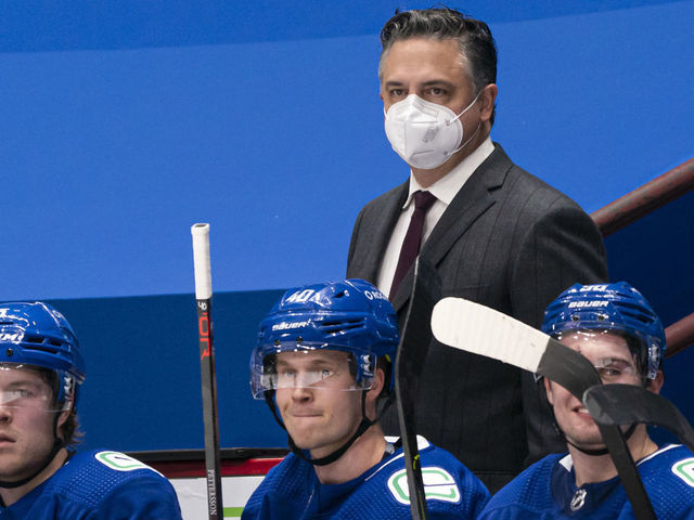 VANCOUVER, BC - FEBRUARY 13: Head coach Travis Green of the Vancouver Canucks behind the bench with players Brock Boeser #6, Elias Pettersson #40 and Nils Hoglander #36 during NHL hockey action against the Calgary Flames at Rogers Arena on February 13, 2021 in Vancouver, Canada.