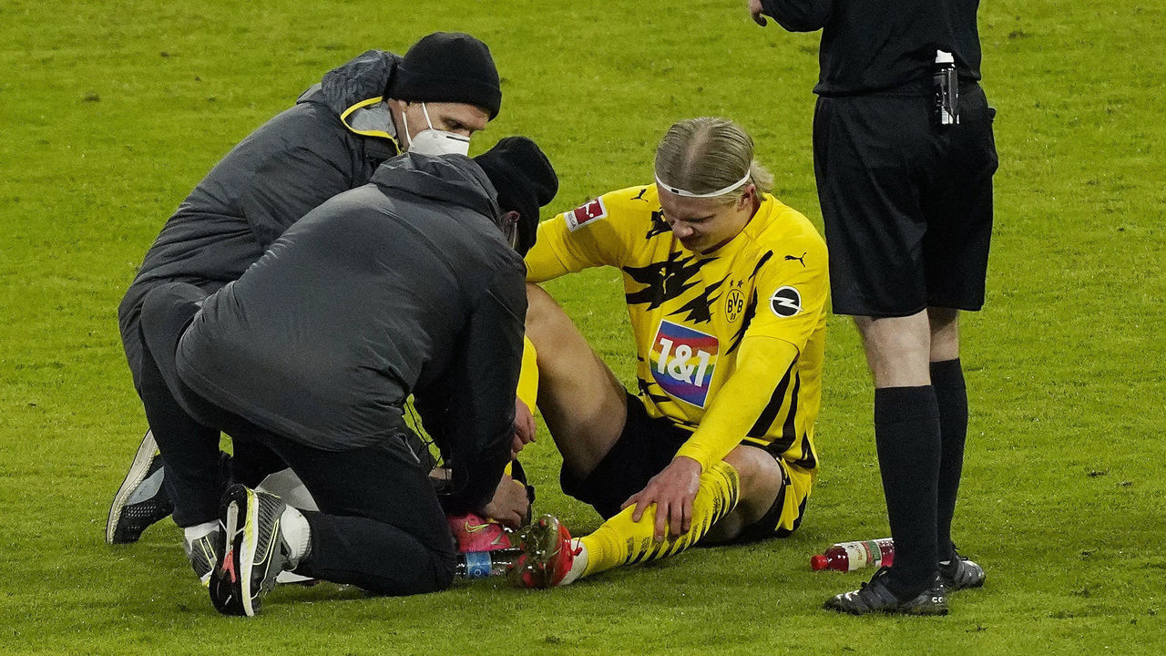 MUNICH, GERMANY - MARCH 06: Erling Haaland of Borussia Dortmund receives medical treatment during the Bundesliga match between FC Bayern Muenchen and Borussia Dortmund at Allianz Arena on March 06, 2021 in Munich, Germany. Sporting stadiums around Germany remain under strict restrictions due to the Coronavirus Pandemic as Government social distancing laws prohibit fans inside venues resulting in games being played behind closed doors.