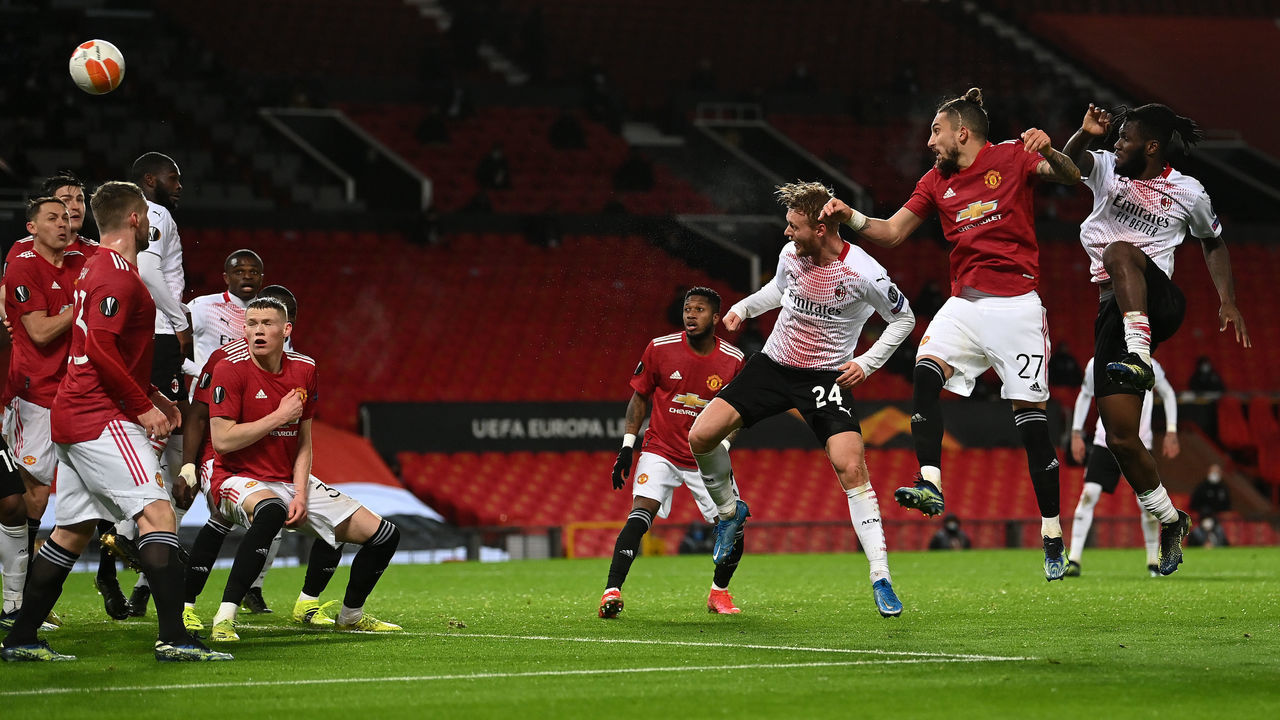 MANCHESTER, ENGLAND - MARCH 11: Simon Kjaer of A.C. Milan scores their team's first goal under pressure from Alex Telles of Manchester United during the UEFA Europa League Round of 16 First Leg match between Manchester United and A.C. Milan at Old Trafford on March 11, 2021 in Manchester, England. Sporting stadiums around the UK remain under strict restrictions due to the Coronavirus Pandemic as Government social distancing laws prohibit fans inside venues resulting in games being played behind closed doors.