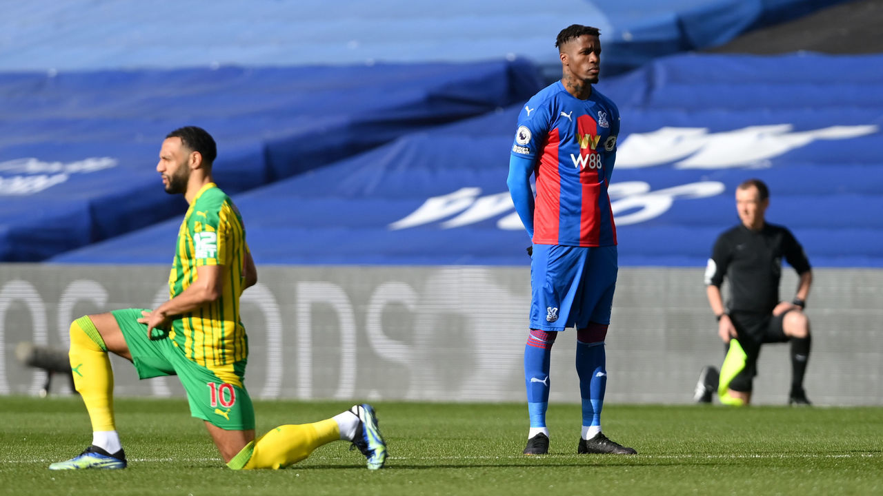 LONDON, ENGLAND - MARCH 13: Wilfried Zaha of Crystal Palace stands at kick off as Matt Phillips of West Bromwich Albion takes a knee in support of the Black Lives Matter movement prior to the Premier League match between Crystal Palace and West Bromwich Albion at Selhurst Park on March 13, 2021 in London, England. Sporting stadiums around the UK remain under strict restrictions due to the Coronavirus Pandemic as Government social distancing laws prohibit fans inside venues resulting in games being played behind closed doors.