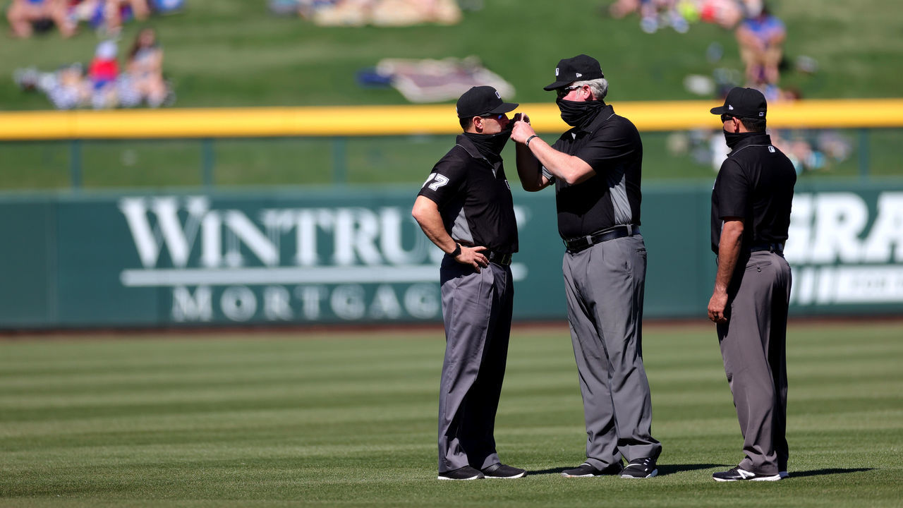 MESA, ARIZONA - MARCH 02: Umpire Jim Reynolds #77 gets some help with his mask during the third inning of a preseason game between the Kansas City Royals and the Chicago Cubs on March 02, 2021 in Mesa, Arizona.