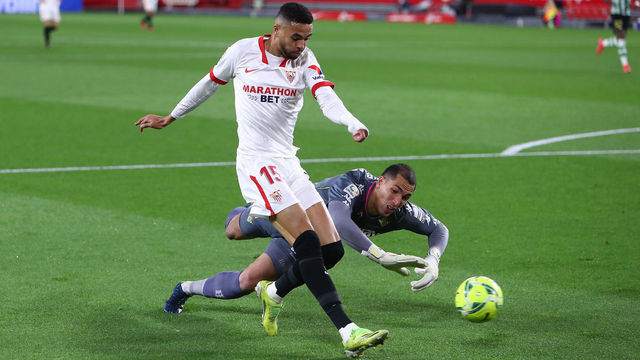 SEVILLE, SPAIN - MARCH 14: Yousseff En-Nesyri of Sevilla scores their side's first goal as he is challenged by Joel Robles of Real Betis during the La Liga Santander match between Sevilla FC and Real Betis at Estadio Ramon Sanchez Pizjuan on March 14, 2021 in Seville, Spain. Sporting stadiums around Spain remain under strict restrictions due to the Coronavirus Pandemic as Government social distancing laws prohibit fans inside venues resulting in games being played behind closed doors.