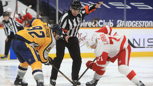 NASHVILLE, TN - MARCH 23: Referee Tim Peel (20) drops the puck for the opening faceoff between Nashville Predators center Ryan Johansen (92) and Detroit Red Wings center Dylan Larkin (71) during the NHL game between the Nashville Predators and Detroit Red Wings, held on March 23, 2021, at Bridgestone Arena in Nashville, Tennessee.