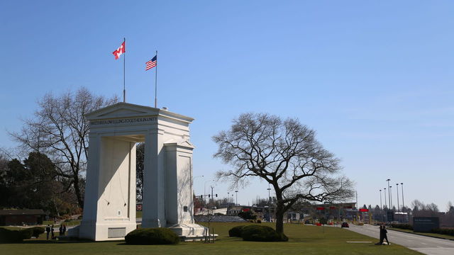 VANCOUVER, BC - MARCH 18 : The Canadian and American flags fly above the Peace Arch Border crossing between Canada and the United States, near Seattle, Washington and Vancouver, British Columbia on March 18, 2020. As a new measure designed to slow the spread of COVID-19, Canada and the U.S. have agreed to temporarily close their shared border to non-essential travel.