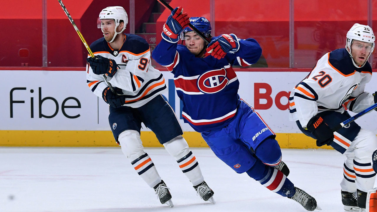 MONTREAL, QC - FEBRUARY 11: Nick Suzuki #14 of the Montreal Canadiens is tripped up by Connor McDavid #97 of the Edmonton Oilers in the NHL game at the Bell Centre on February 11, 2021 in Montreal, Quebec, Canada.
