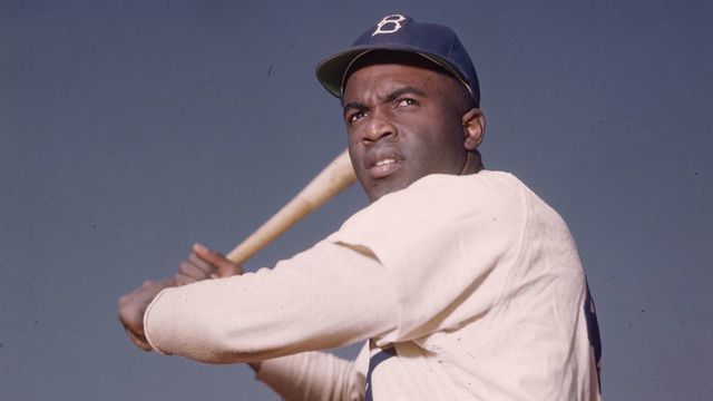 circa 1945: A portrait of the Brooklyn Dodgers' Jackie Robinson in uniform, preparing to swing a baseball bat.