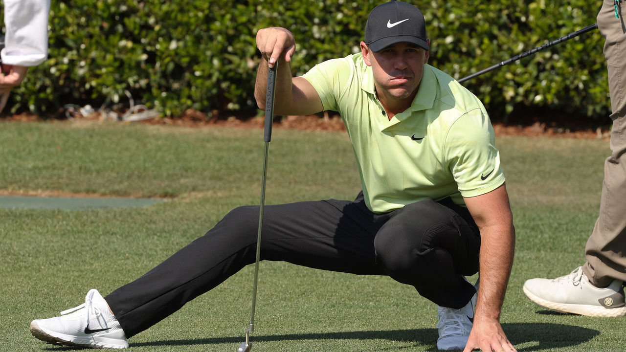 AUGUSTA, GEORGIA - APRIL 06: Brooks Koepka of the United States crouches as he lines up a putt on the practice green during a practice round prior to the Masters at Augusta National Golf Club on April 06, 2021 in Augusta, Georgia.