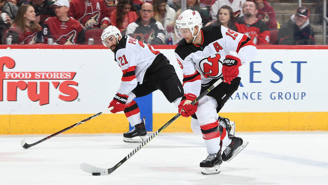 GLENDALE, AZ - JANUARY 04: Travis Zajac #19 of the New Jersey Devils skates the puck up ice along side of teammate Kyle Palmieri #21 against the Arizona Coyotes at Gila River Arena on January 4, 2019 in Glendale, Arizona.