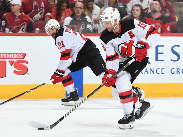 GLENDALE, AZ - JANUARY 04: Travis Zajac #19 of the New Jersey Devils skates the puck up ice along side of teammate Kyle Palmieri #21 against the Arizona Coyotes at Gila River Arena on January 4, 2019 in Glendale, Arizona.