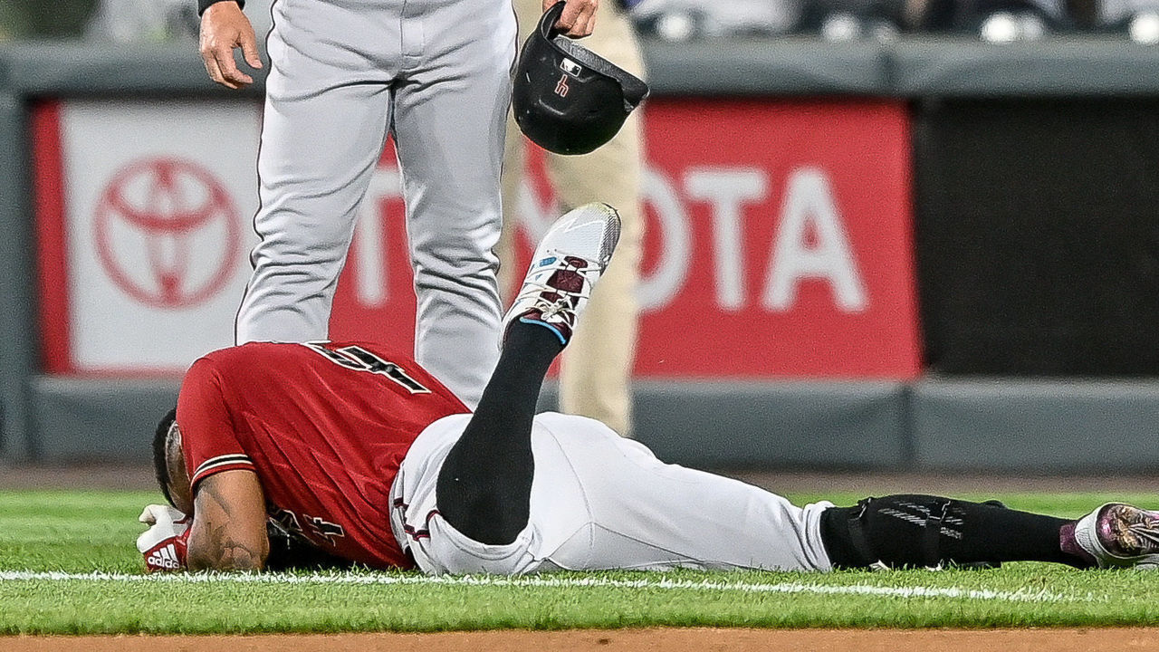 DENVER, CO - APRIL 07: Arizona Diamondbacks second baseman Ketel Marte (4) lies on the ground with an apparent lower body injury as quality control/catching coach Robby Hammock (7) looks on during a game between the Colorado Rockies and the Arizona Diamondbacks at Coors Field in Denver, Colorado on April 7, 2021.
