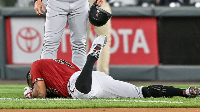 DENVER, CO - APRIL 07: Arizona Diamondbacks second baseman Ketel Marte (4) lies on the ground with an apparent lower body injury as quality control/catching coach Robby Hammock (7) looks on during a game between the Colorado Rockies and the Arizona Diamondbacks at Coors Field in Denver, Colorado on April 7, 2021.