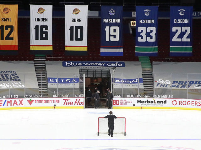 VANCOUVER, BC - MARCH 31: A rink attendant pushes a game net off the ice after the NHL game between the Calgary Flames and the Vancouver Canucks was postponed due to a positive COVID test result of a player at Rogers Arena on March 31, 2021 in Vancouver, British Columbia, Canada.