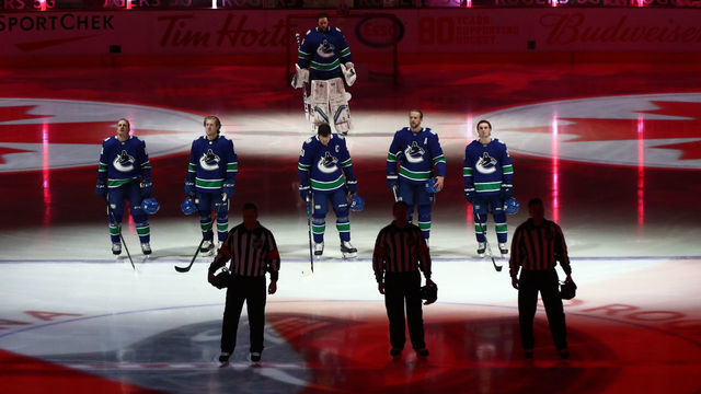VANCOUVER, BC - MARCH 24: The Vancouver Canucks listen to the Canadian Anthem before playing the Winnipeg Jets during their NHL game at Rogers Arena on March 24, 2021 in Vancouver, British Columbia, Canada.
