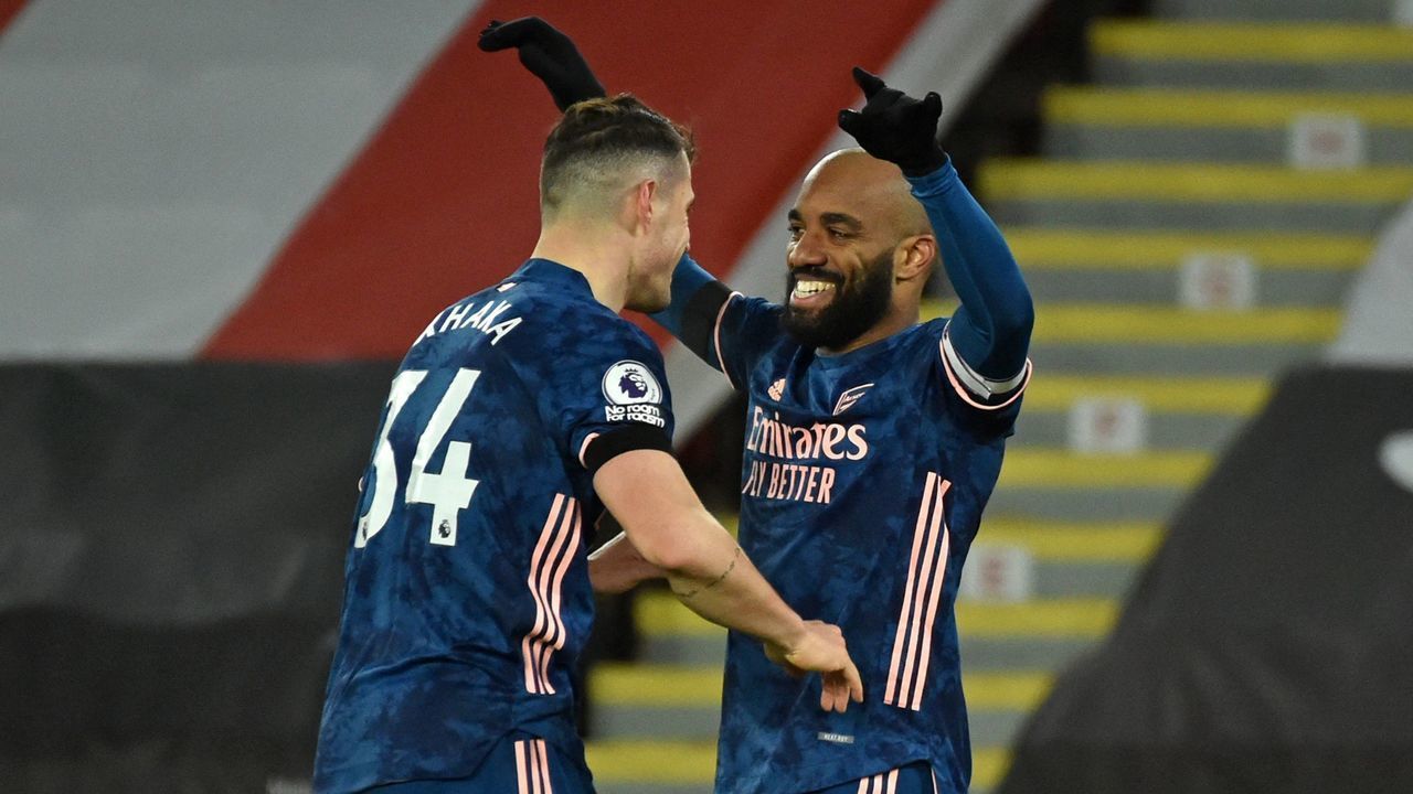 Arsenal's French striker Alexandre Lacazette (R) celebrates with Arsenal's Swiss midfielder Granit Xhaka (L) after scoring their third goal during the English Premier League football match between Sheffield United and Arsenal at Bramall Lane in Sheffield, northern England on April 11, 2021. - RESTRICTED TO EDITORIAL USE. No use with unauthorized audio, video, data, fixture lists, club/league logos or 'live' services. Online in-match use limited to 120 images. An additional 40 images may be used in extra time. No video emulation. Social media in-match use limited to 120 images. An additional 40 images may be used in extra time. No use in betting publications, games or single club/league/player publications.