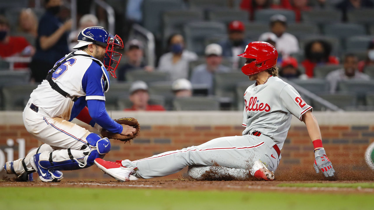 ATLANTA, GA - APRIL 11: Alec Bohm #28 of the Philadelphia Phillies slides into home plate ahead of the tag by Travis d'Arnaud #16 of the Atlanta Braves for the go-ahead run in the ninth inning against the Atlanta Braves at Truist Park on April 11, 2021 in Atlanta, Georgia.