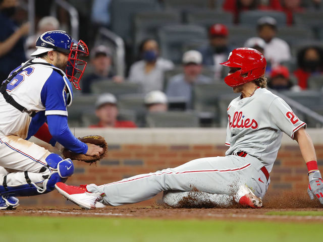 ATLANTA, GA - APRIL 11: Alec Bohm #28 of the Philadelphia Phillies slides into home plate ahead of the tag by Travis d'Arnaud #16 of the Atlanta Braves for the go-ahead run in the ninth inning against the Atlanta Braves at Truist Park on April 11, 2021 in Atlanta, Georgia.