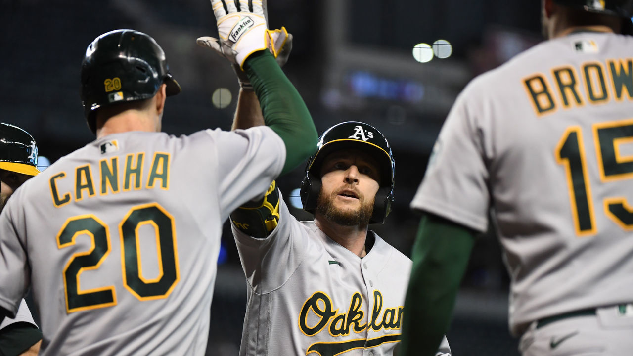 PHOENIX, ARIZONA - APRIL 13: Jed Lowrie #8 of the Oakland Athletics celebrates with Mark Canha #20 and Seth Brown #15 after hitting a three run home run off of Kevin Ginkel #37 of the Arizona Diamondbacks during the seventh inning at Chase Field on April 13, 2021 in Phoenix, Arizona. Ahmed was forced out at first base.