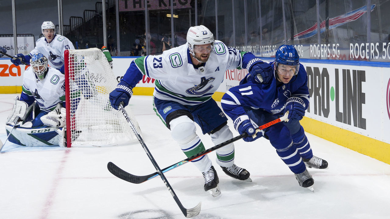 TORONTO, ON - FEBRUARY 4: Zach Hyman #11 of the Toronto Maple Leafs battles against Alexander Edler #23 of the Vancouver Canucks during the first period at the Scotiabank Arena on February 4, 2021 in Toronto, Ontario, Canada.